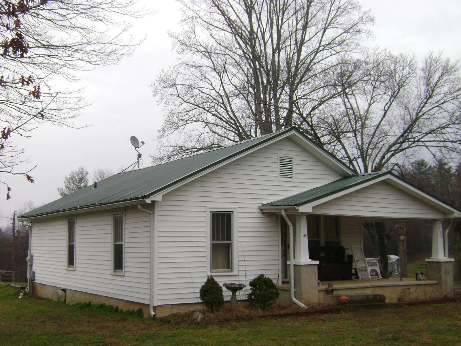 Green metal roof on a white bungalow with a side porch in Lake Mills