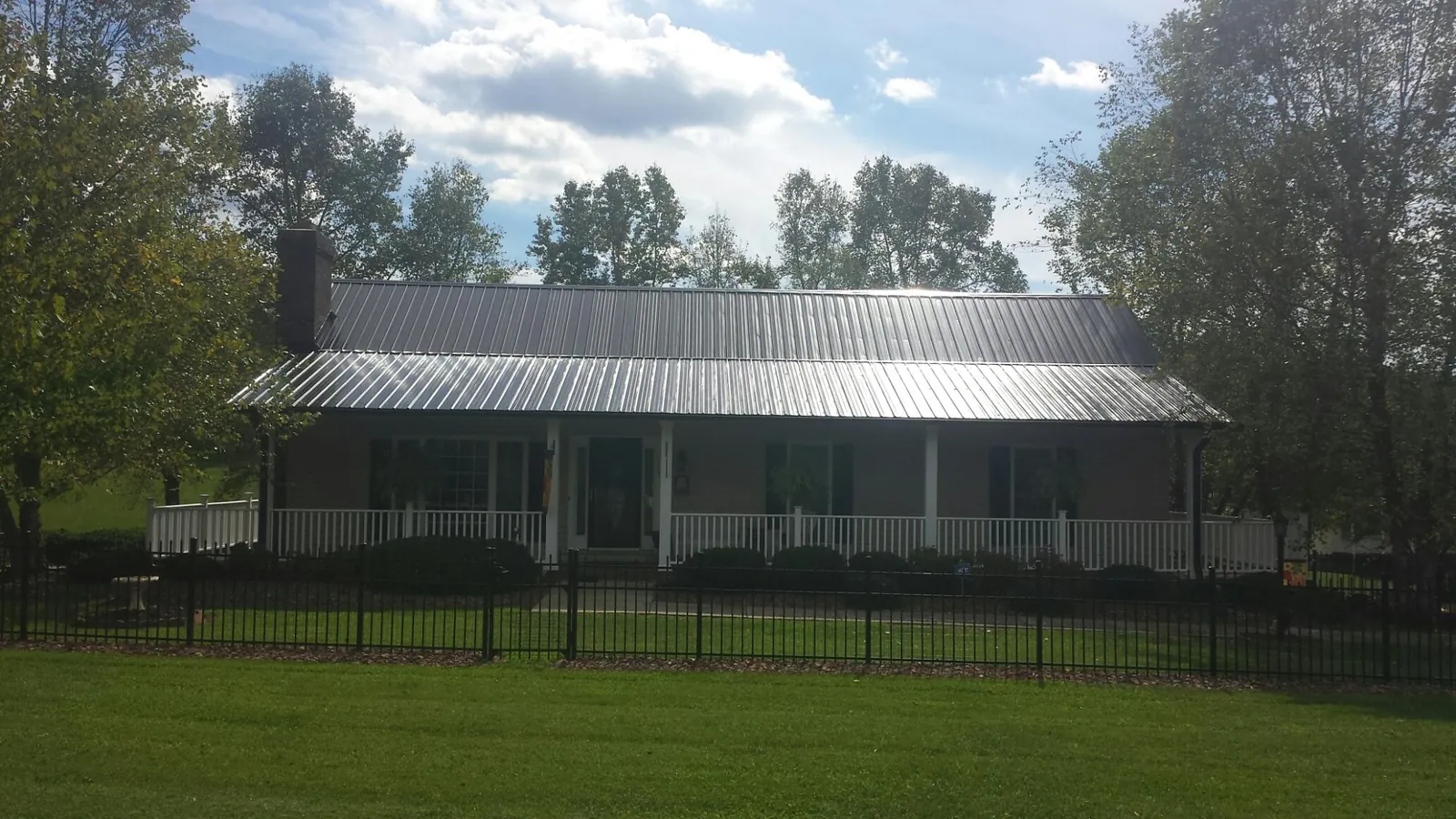 Gray metal roof on a brick ranch with a full width front porch — Gutter Guard Installation work by our crew in Lake Mills